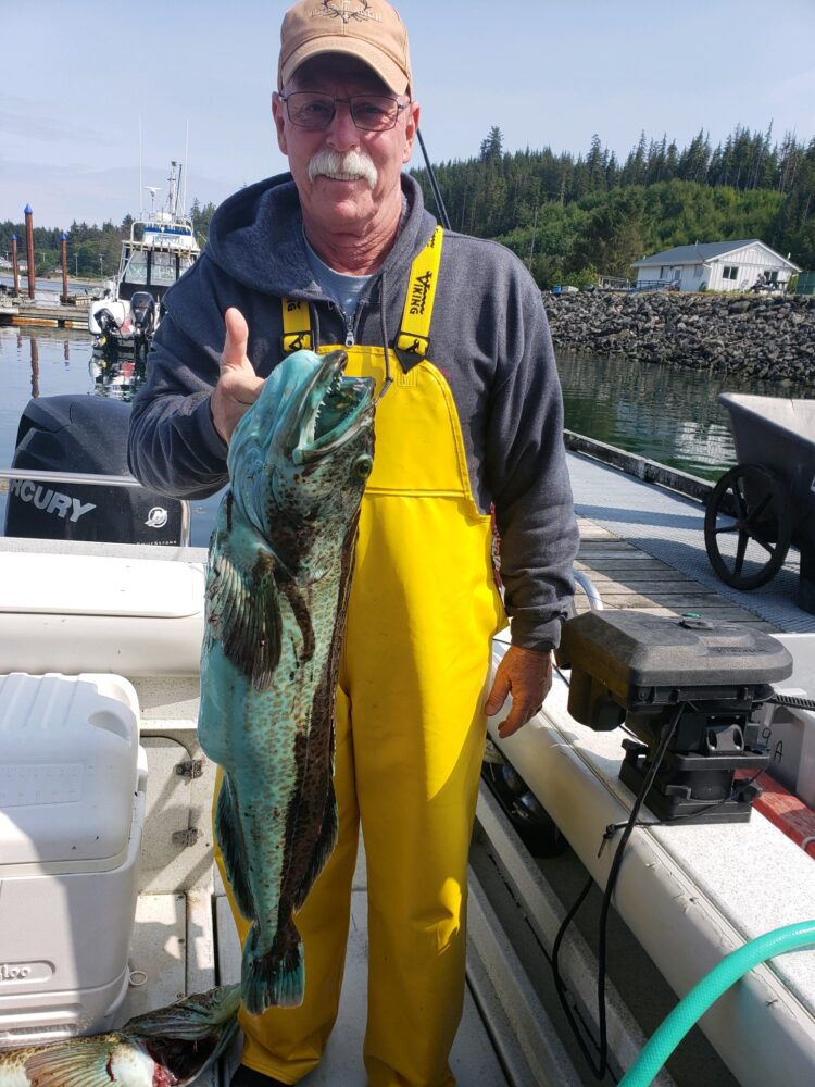 Dennis holding a green Haida Gwaii Lingcod on a Queen Charlotte Safaris boat
